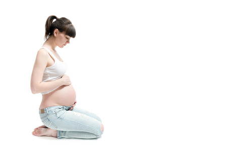 pregnant woman touching her belly with hands isolated on whiteの写真素材