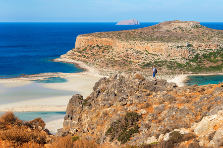 traveler with a backpack stands on a rock and looks at the panorama of the Balos beach, Crete, Greeceの写真素材
