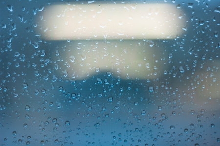 Drops of rain on window glass with lights bokeh