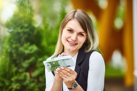 Happy girl holding a stack of euro banknotes and smiling. Business, income, success concept