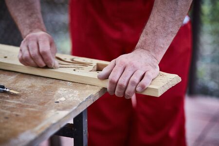 Closeup of male hands carpenter using sandpaper to sand wooden detailの写真素材
