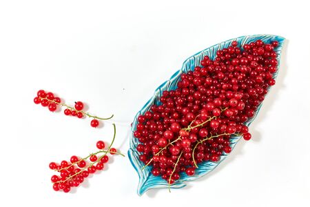 Fresh red currants in plate on a white table. View from above. Space for text