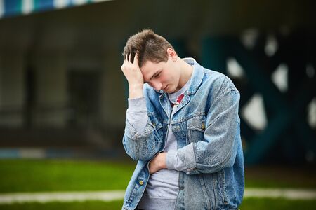 A handsome guy clutched his head, trying to remember something, massaging his head.