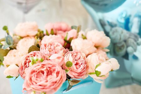 composition of artificial pink peonies in a blue box. postcard