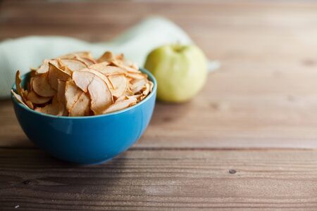 The concept of useful raw food diet. Apple chips and apple on a wooden background.