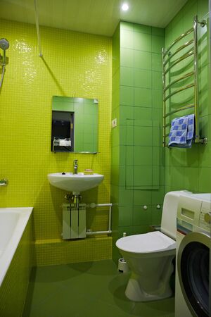 bathroom in green and yellow. Toilet bowl, sink, washing machine, bathtubの写真素材