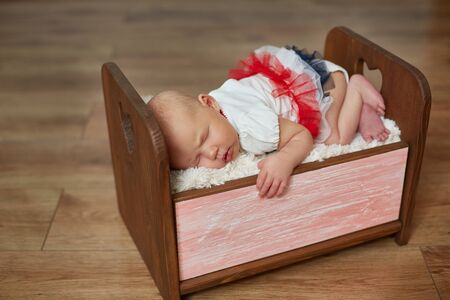 Photoshoot of a newborn in a wooden crib. The girl sleeps in a small crib.の写真素材