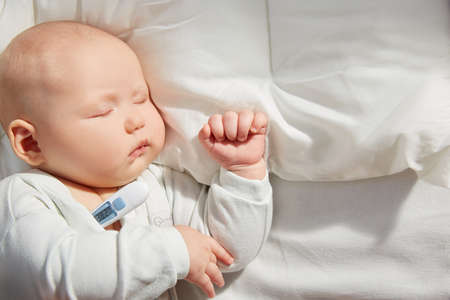 Cute baby sleeping on a pillow with a thermometer. Measure the temperature. copyspace.の写真素材