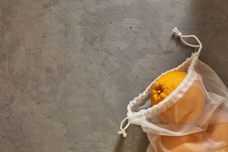 Reusable eco-bag with oranges on a concrete background. Copyspaceの写真素材