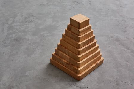Wooden toy pyramid on grey concrete background. Copyspase.の写真素材