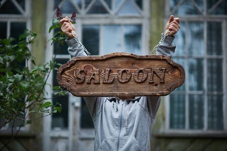 Mans hands holds an old wooden signboard with the words "Salon".の写真素材