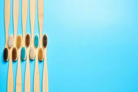 Wooden toothbrushes on a blue background top view with copy space.