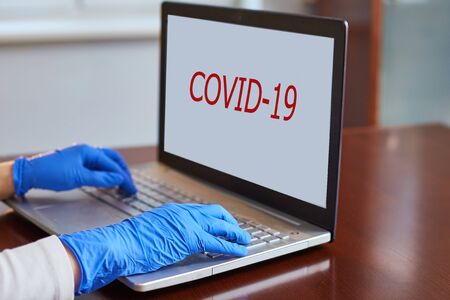 protection against Coronovirus. hands in blue gloves are typing on a laptop keyboard.の写真素材