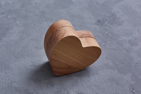 A wooden heart made using cnc. lies on a concrete background with spears of space. Symbol of love and Valentine's Day.の写真素材