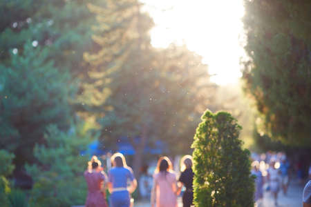 People walk down the street on a sunny summer day. Blurry out of focus view.の写真素材