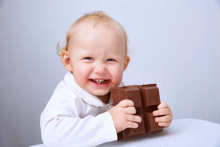 Baby eats a large bar of chocolateの写真素材