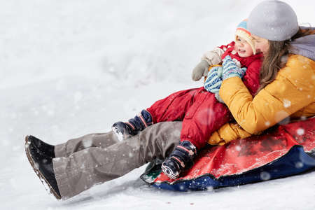 Winter entertainment. Active woman and her child ride down the mountain in winter on a tubing.