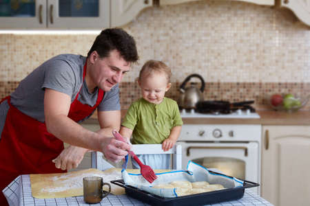 Father and child bake pies, cook food and have fun in the kitchen. Homemade food and a little helper. Happy parenthoodの写真素材