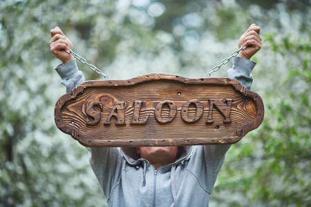 Woodworking. A man holds a sign made of wood with the inscription saloonの写真素材