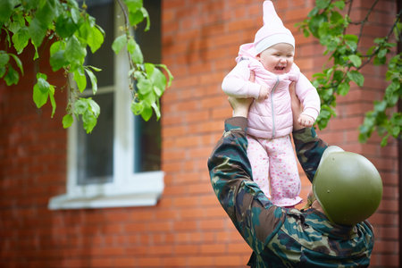 Military father came from the war or the exercises and cheerfully throws the baby.の写真素材