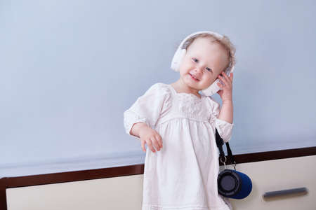 Toddler in a boho dress dances to the music with headphones and a music speaker. Copy spaceの写真素材