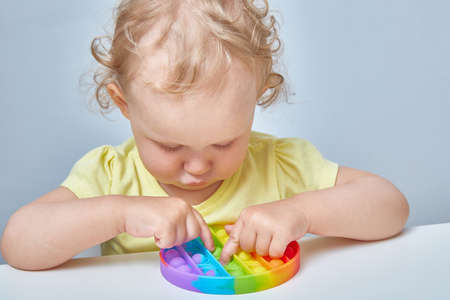 A curly-haired child grabs an anti-stress toy in the ass. Education of children with the help of popular games.の写真素材