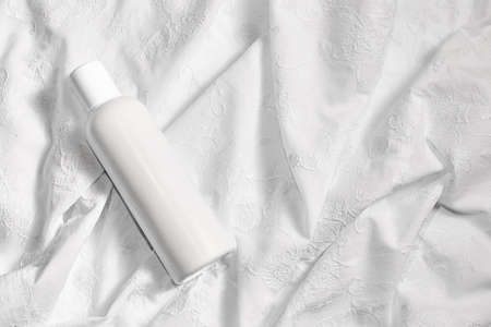 White cosmetic bottle on white fabric with space for text.の写真素材