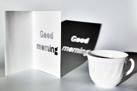 White cup on a white table in the morning with sun shadows. Black and white monochrome toneの写真素材