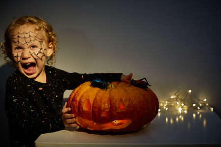Happy Halloween. Cute little funny baby with a big Jack OLantern pumpkin. Copy space.の写真素材