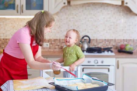 Mom and little daughter cook pies in the kitchen at homeの写真素材