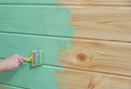 hand paints a wooden vertical surface with green paint.の写真素材