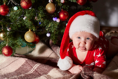 Caucasian baby shows his tongue and crawls under the Christmas tree at home. lifestyle. copy spaceの写真素材