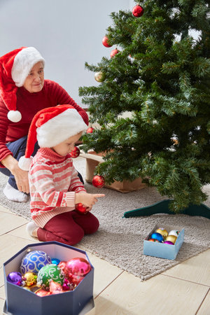 Christmas holidays. Grandma and granddaughter decorate the house with Christmas toys and balls.の写真素材