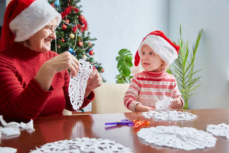 Christmas and New Year time. Grandma makes crafts with her own hands together with her little granddaughterの写真素材