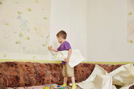 boy tears the wallpaper off the wall. Preparing for home repair workの写真素材