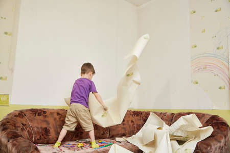 boy tears off the stained wallpaper on the wall in the room. Mental problems and mental health during lockdownの写真素材