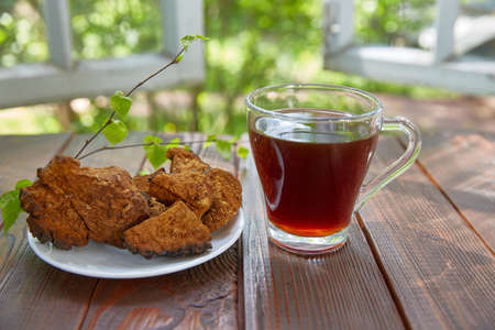 cup of tea with chaga and a dried chaga mushroom lies next to it on a plateの写真素材