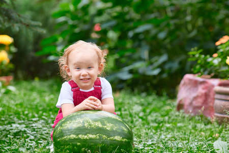 child on a picnic with a watermelon on a sunny summer day. Health, walking, healthy food.の写真素材