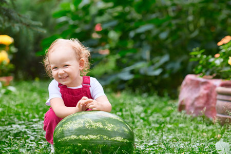 child smiles cheerfully in summer with a watermelon in his hands. Health, walking, healthy food.の写真素材