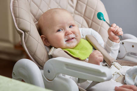 smiling happy baby with a spoon in his hands tries the first milk lure feeding.の写真素材