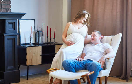 young family with a pregnant woman in the living room of their new modern houseの写真素材