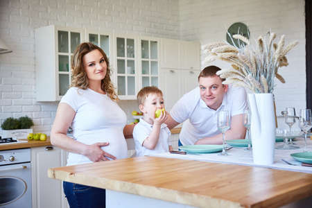 happy family with a young son and a pregnant woman in the kitchen.の写真素材