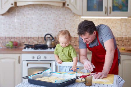 Dad and a small child cook together in the kitchen. The concept of family and mutual understanding. Fatherhood and parenthood.の写真素材