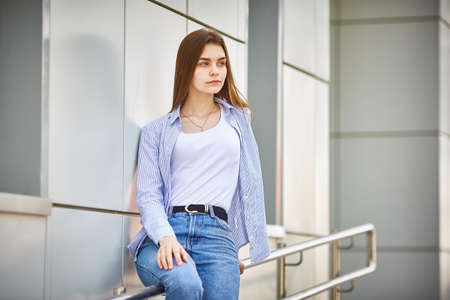 Sad teen girl with sitting on the railing of a building. Psychological problems of teenagersの写真素材