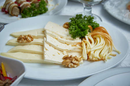 Different sorts of cheese. Cheese plate in the restaurant with different types of cheese, decorated with herbs and walnuts.の写真素材