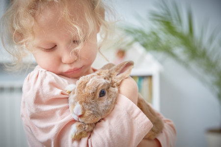 curly-haired girl gently hugs a rabbit in the living room of the house. Close-upの写真素材
