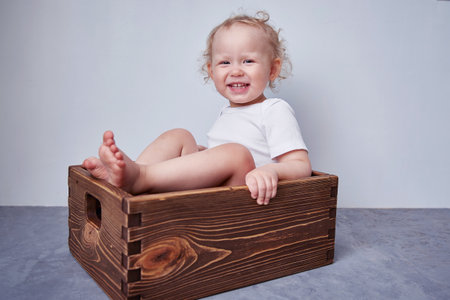 kid is sitting in an old wooden box for a newborn shoot.の写真素材
