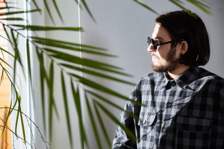 The young man looks thoughtfully out of the windowの写真素材