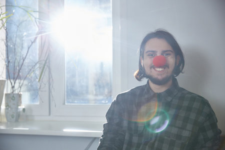 Portrait of a man in with a clown nose. the guy smiles stupidly. Lifestyle. Copy spaceの写真素材
