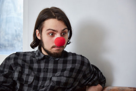 Portrait of a man in with a clown nose. the guy smiles stupidly. Lifestyle.の写真素材